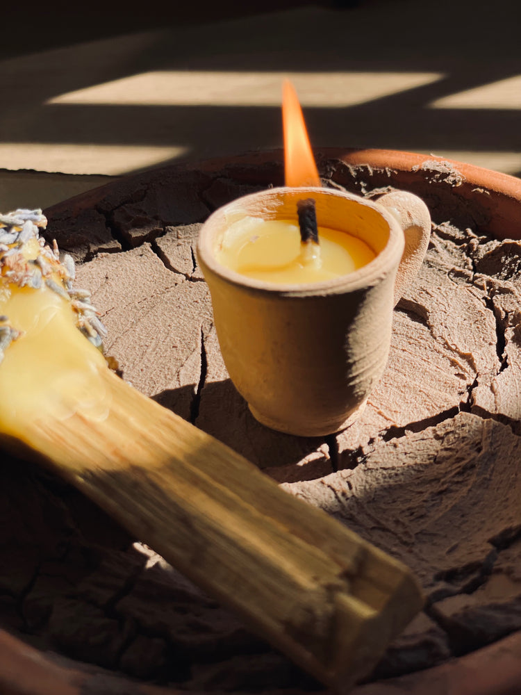 lit mini beeswax candle next to palo santo stick